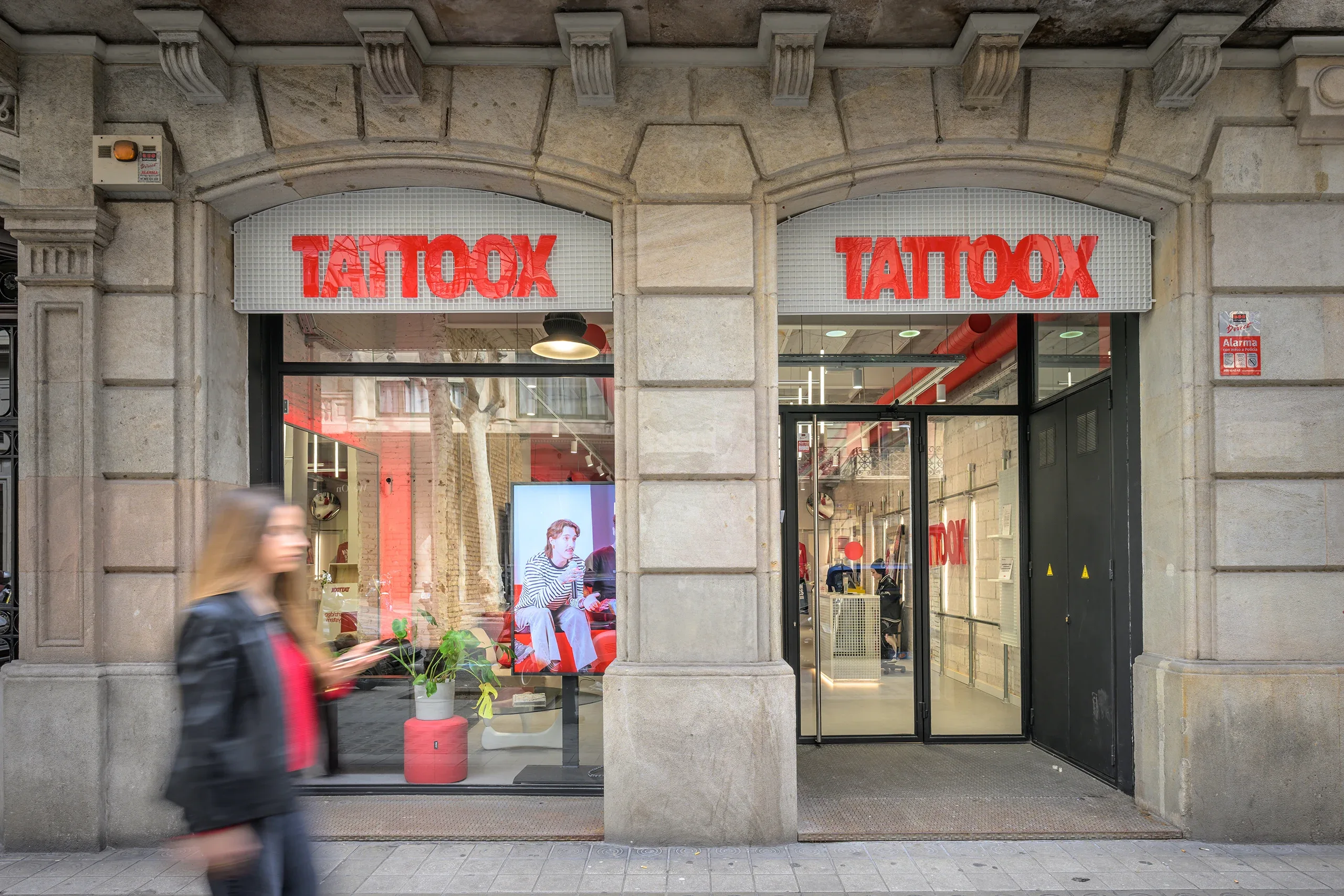 Fachada de Tattoox Club en Barcelona con rótulos rojos sobre tramex y arcos de piedra del edificio histórico, diseño de huuun