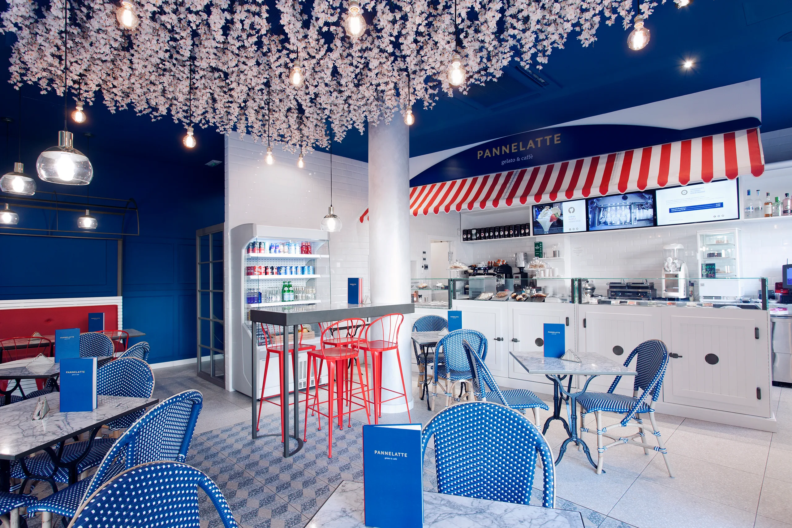 Salón de Pannelatte con toldo de rayas rojas y blancas sobre el mostrador y taburetes rojos