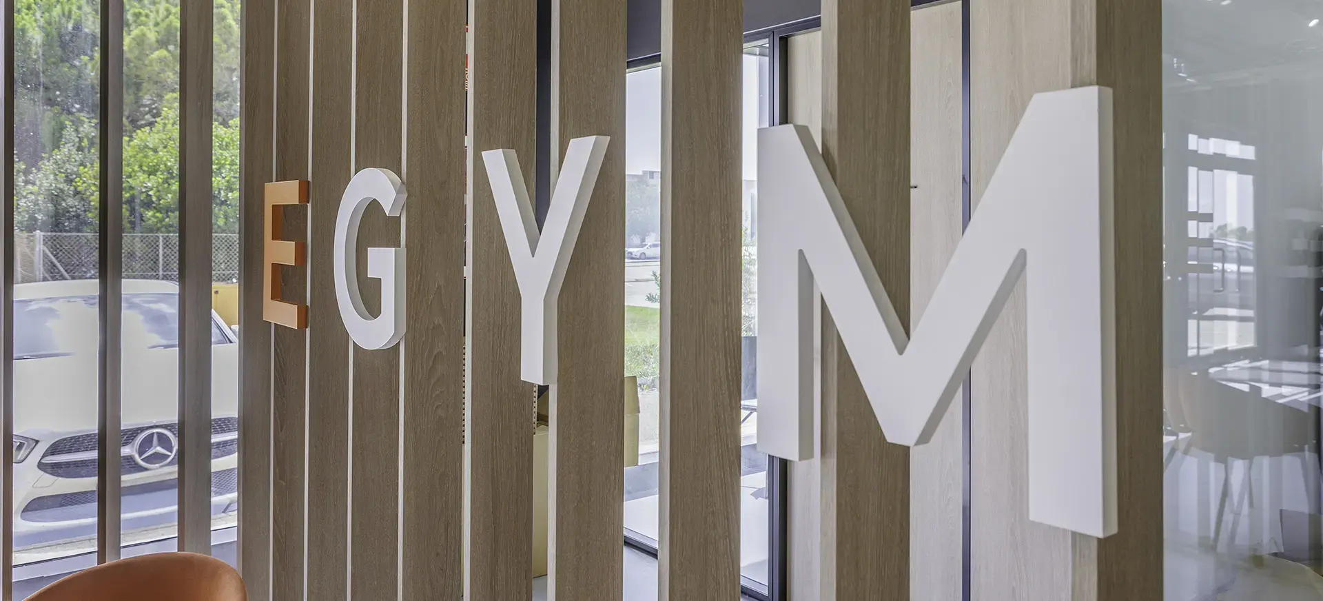 Detalle del logotipo EGYM en letras corpóreas sobre celosía de madera en la entrada de EGYM Fitness Lab en Valencia