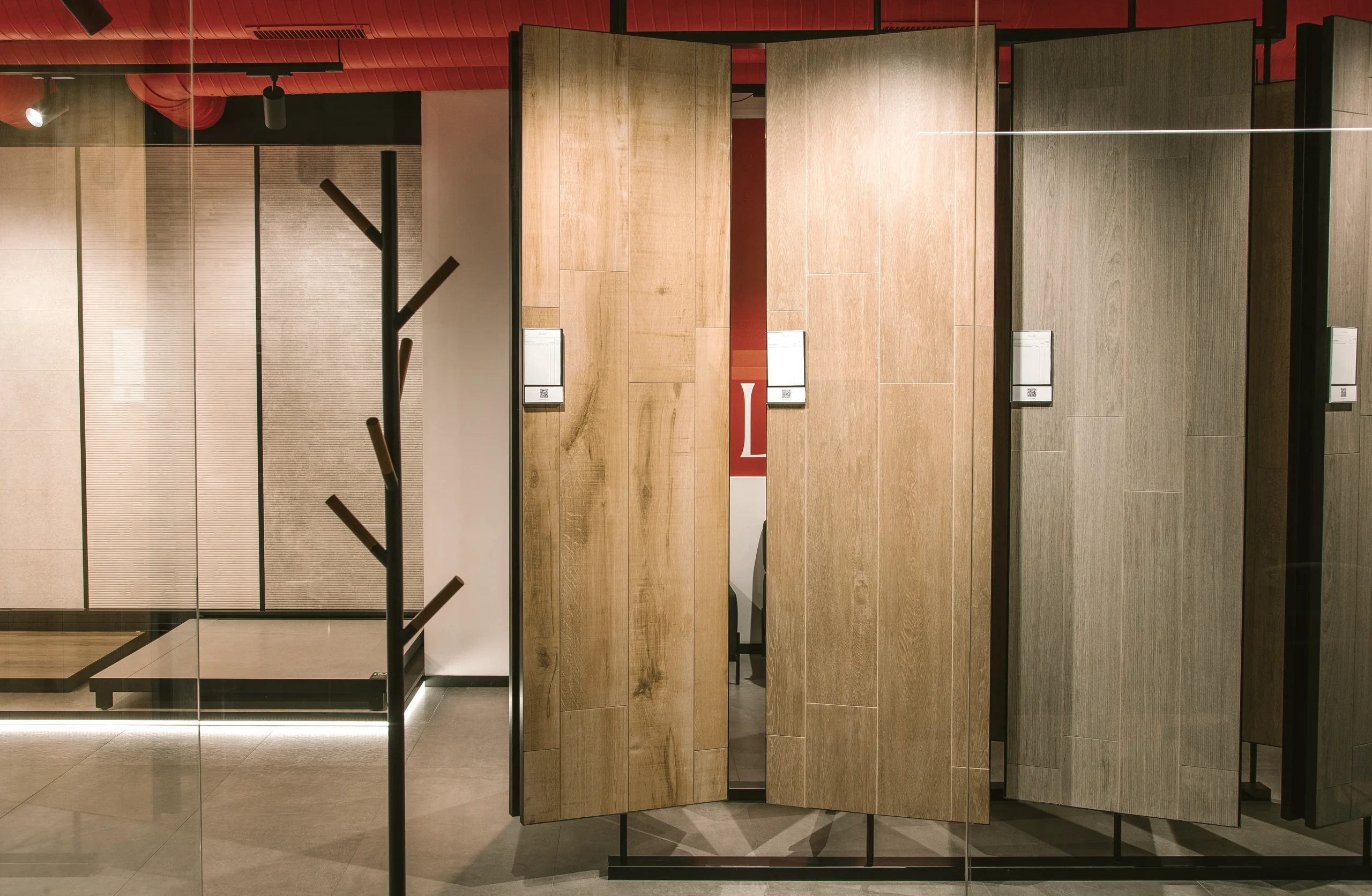 Paneles giratorios de cerámica imitación madera con etiquetas de código QR junto a un perchero de madera en la flagship de SALONI en Madrid
