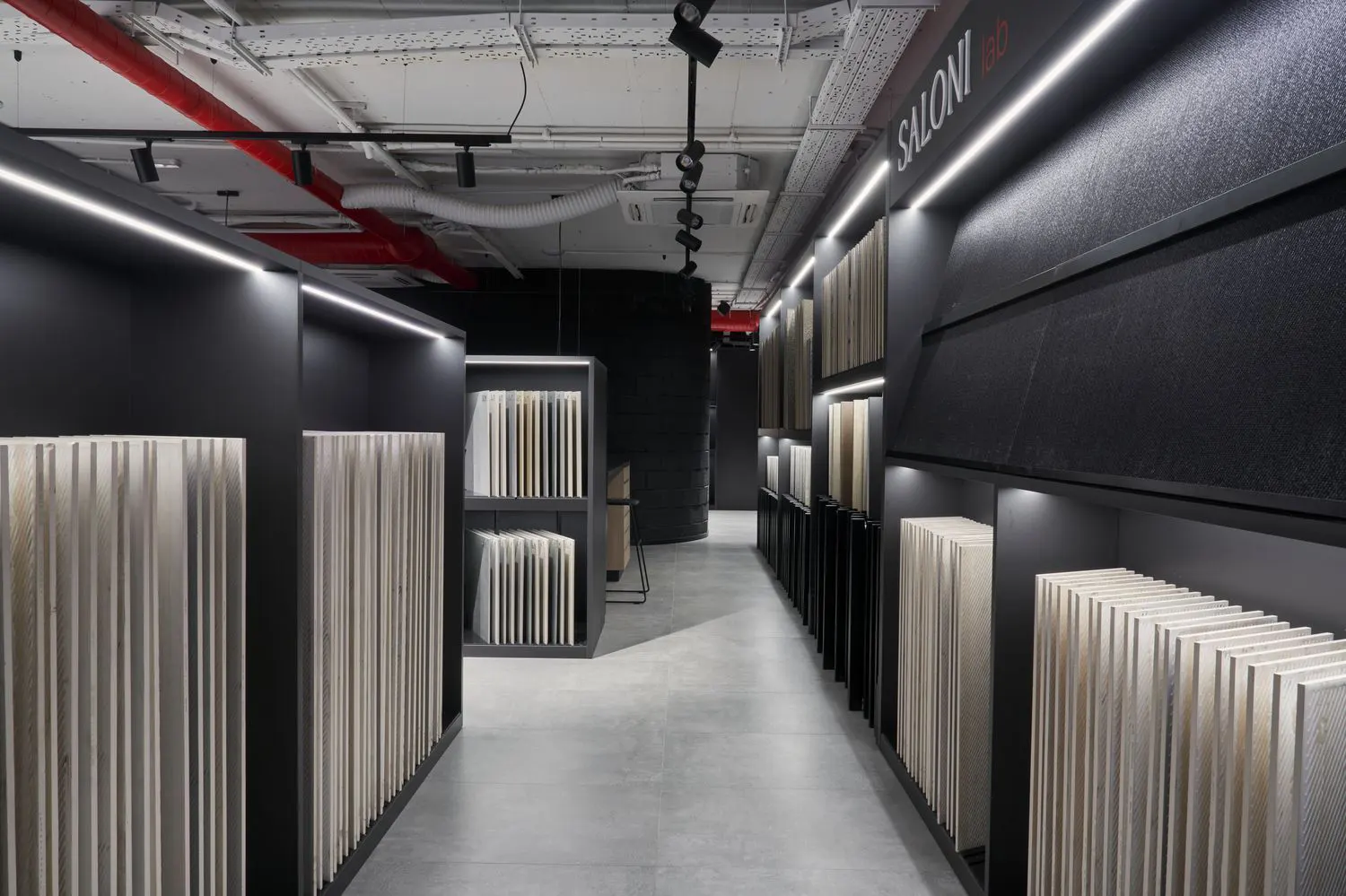 Estanterías negras con muestrario vertical de baldosas cerámicas y mesa de trabajo en el área SALONI lab de la flagship de Madrid
