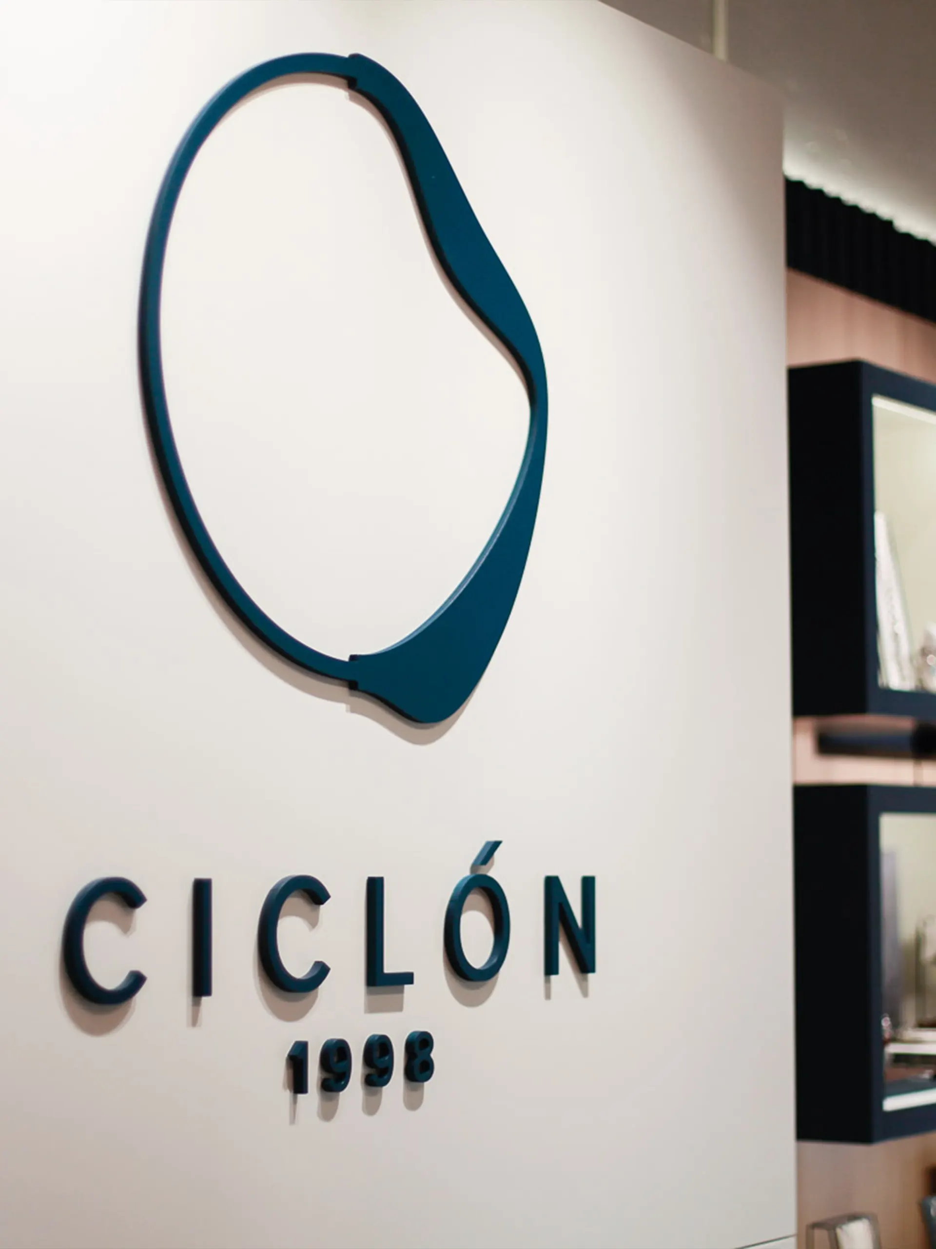 Logotipo de Ciclón en relieve sobre pared blanca, diseño de interiorismo de huuun