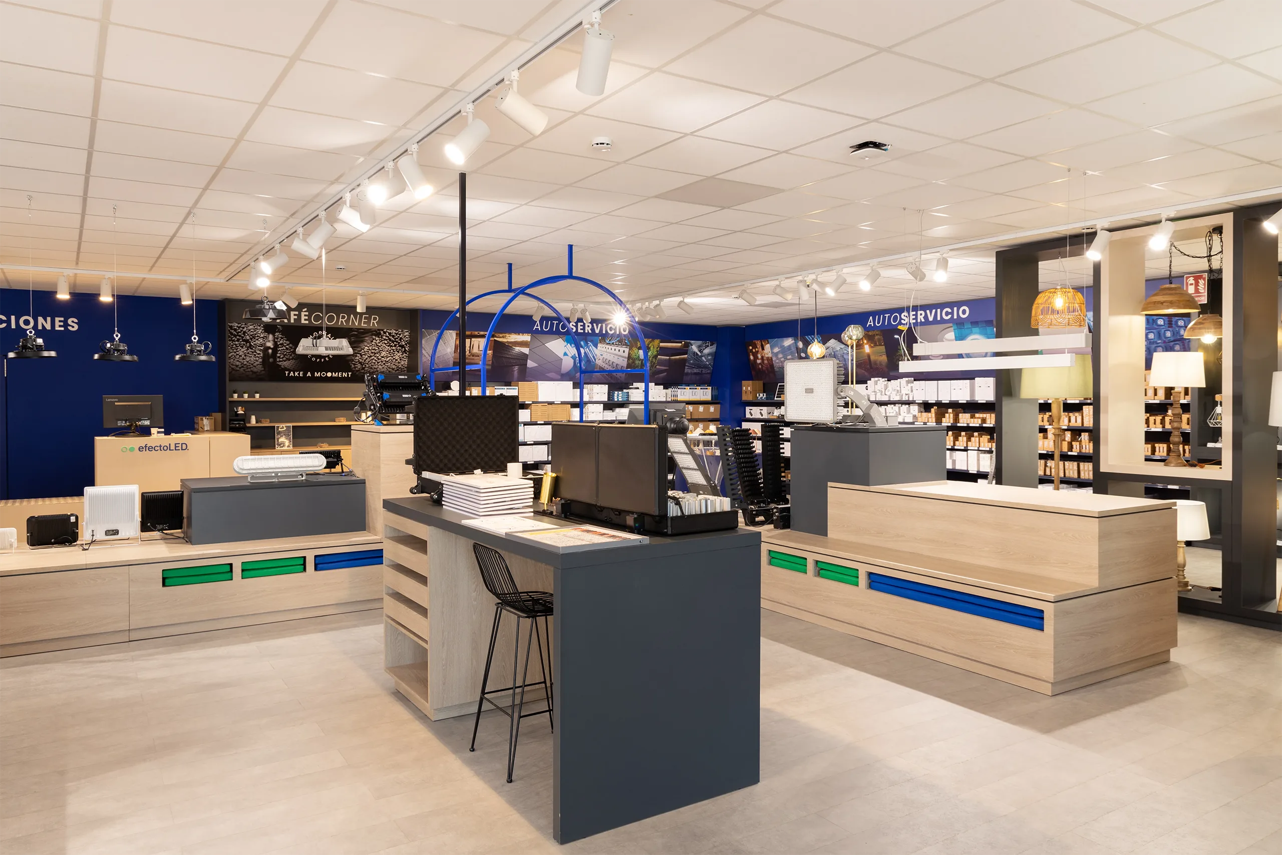 Zona de autoservicio de efectoLED en Catarroja con estanterías de producto, arco de acceso azul y la cafetería Café Corner al fondo
