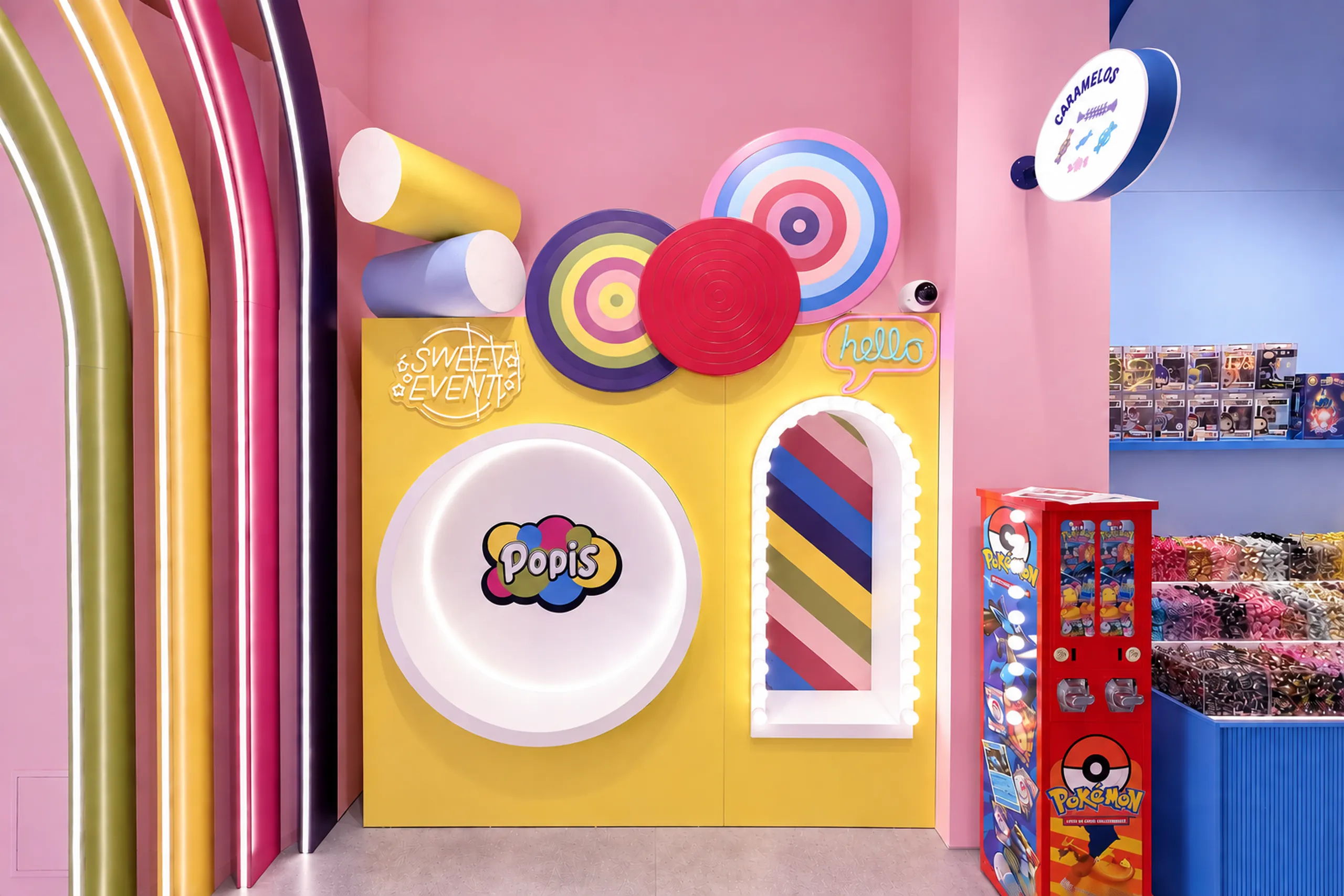 Pared decorativa de POPIS Valencia con logotipo, caramelos gigantes, neón «hello» y máquina expendedora de cartas Pokémon