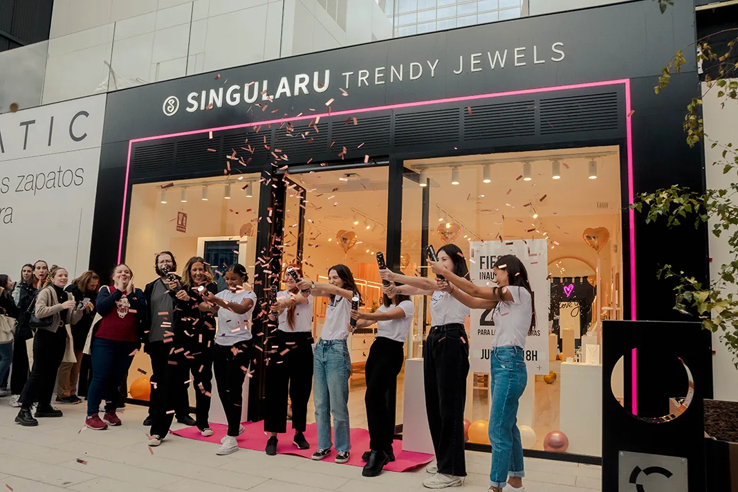 Equipo de Singularu lanzando confeti frente a la fachada con neón rosa en la inauguración de una tienda