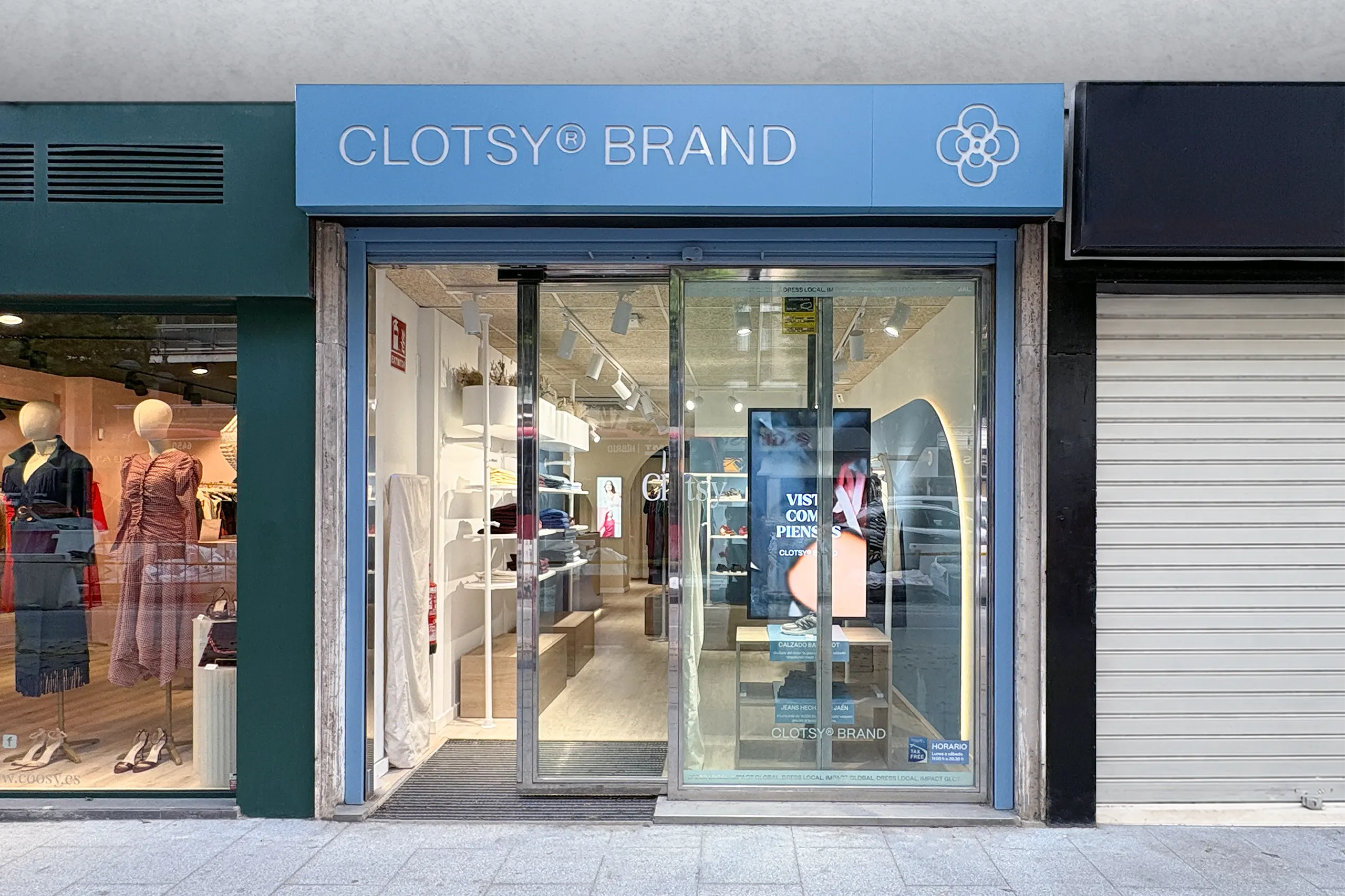 Fachada de la tienda Clotsy Brand con rótulo azul, isotipo floral y escaparate acristalado que deja ver el interior blanco y azul