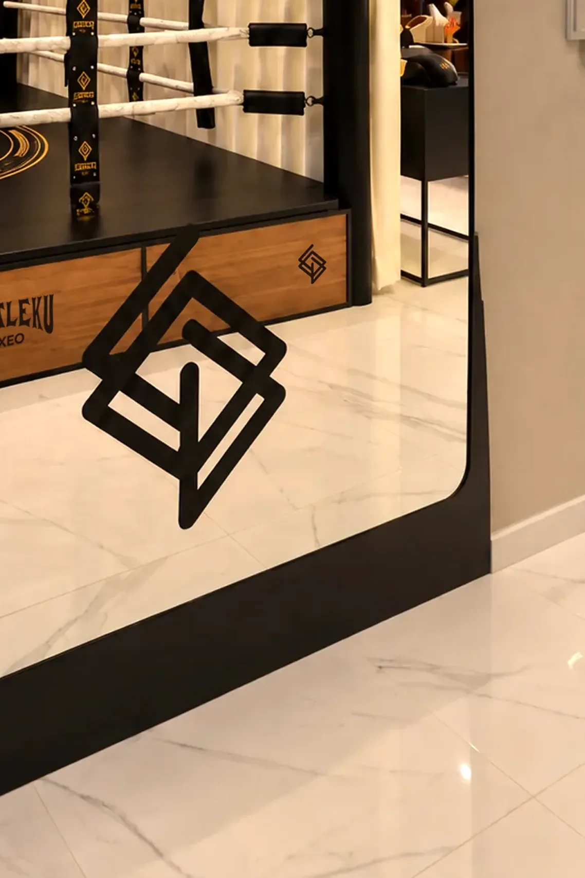 Mampara de cristal con vinilo negro del logotipo Echaleku frente a la base del ring de boxeo