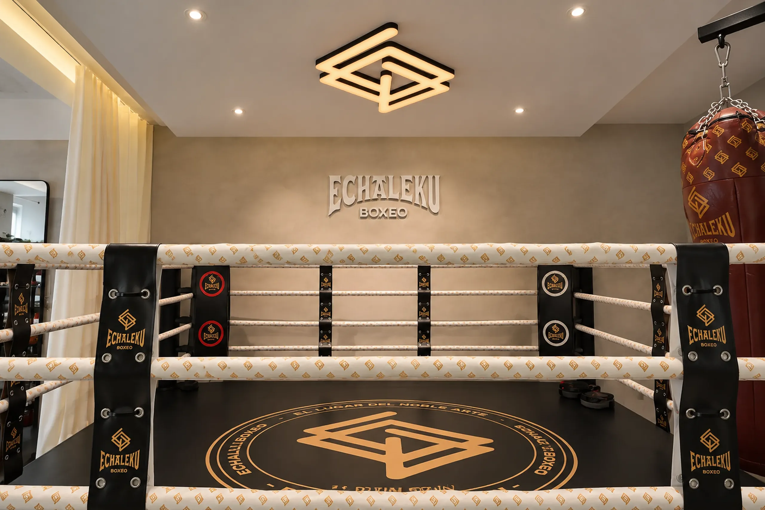 Ring de boxeo en el centro de la tienda Echaleku de Valencia con lámpara de techo con logotipo y saco de boxeo