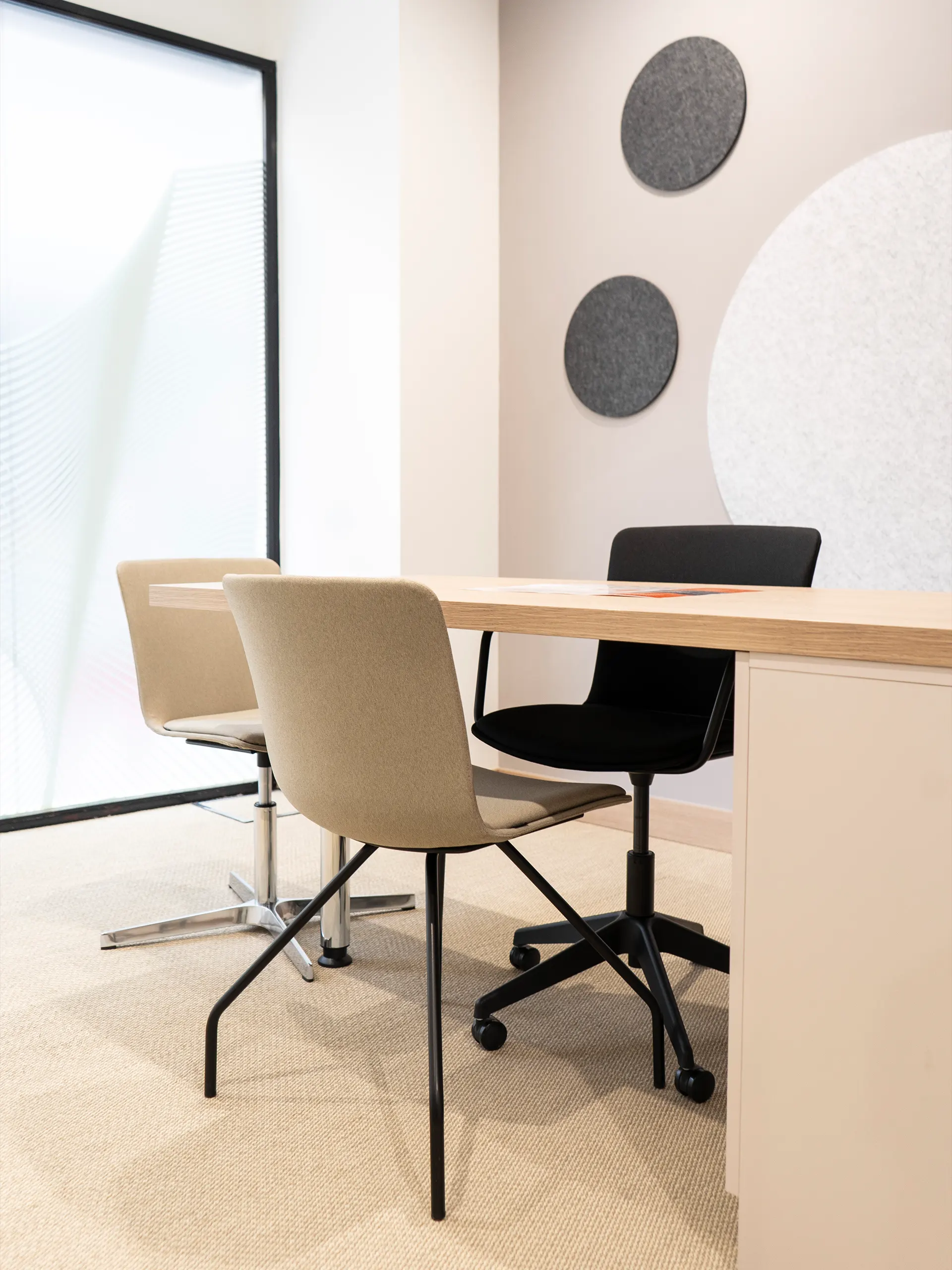 Sala de consulta de GrandAudition con mesa de madera, sillas tapizadas en beige y negro y paneles acústicos circulares en la pared